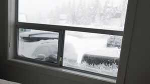 Un dormitorio con ventana que da a un estacionamiento nevado.