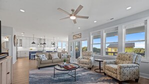 A spacious living room with a sofa, two patterned armchairs, a coffee table, and a ceiling fan. - Luxury beach home w/oceanviews, 5-BR private pool, elevator, only steps to beach (North Topsail Beach)