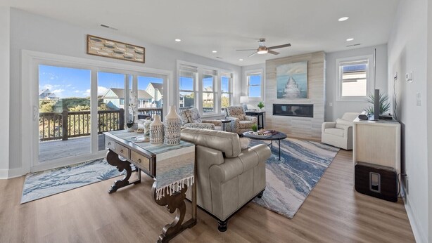 A spacious living room with large windows, a ceiling fan, and a view of the surrounding area. - Luxury beach home w/oceanviews, 5-BR private pool, elevator, only steps to beach (North Topsail Beach)