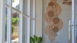 Una sala de estar moderna con un sofá gris, una planta en maceta y una obra de arte tejida colgada en la pared.