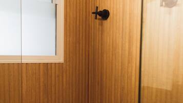 A wooden-paneled bathroom with a showerhead, a window, and a door.