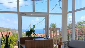 Un interior moderno con ventanas amplias, una mesa de madera central, un sofá y lámparas de mimbre colgantes.