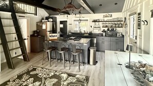 Una cocina moderna con una isla central, taburetes de bar y una lámpara colgante.