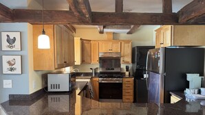 Una cocina con armarios de madera, un refrigerador de acero inoxidable, un microondas y una estufa.