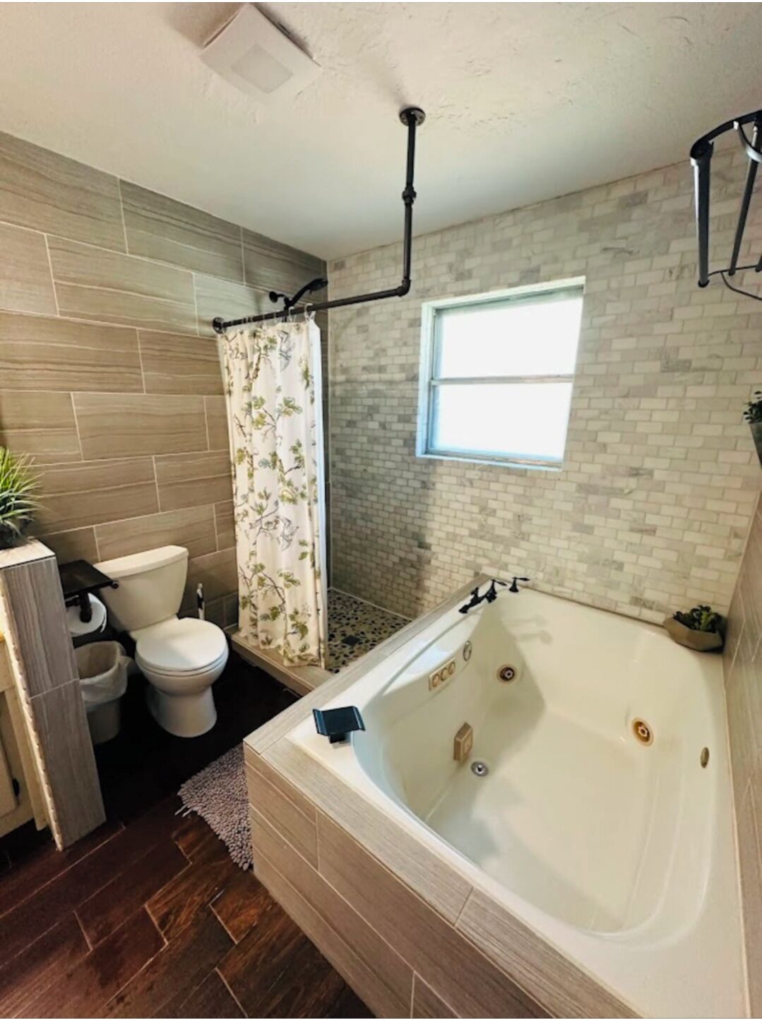 Een badkamer met bad, toilet, douche en een raam.