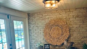 A rustic interior with a wooden ceiling, a stone wall, and a large woven wall hanging.