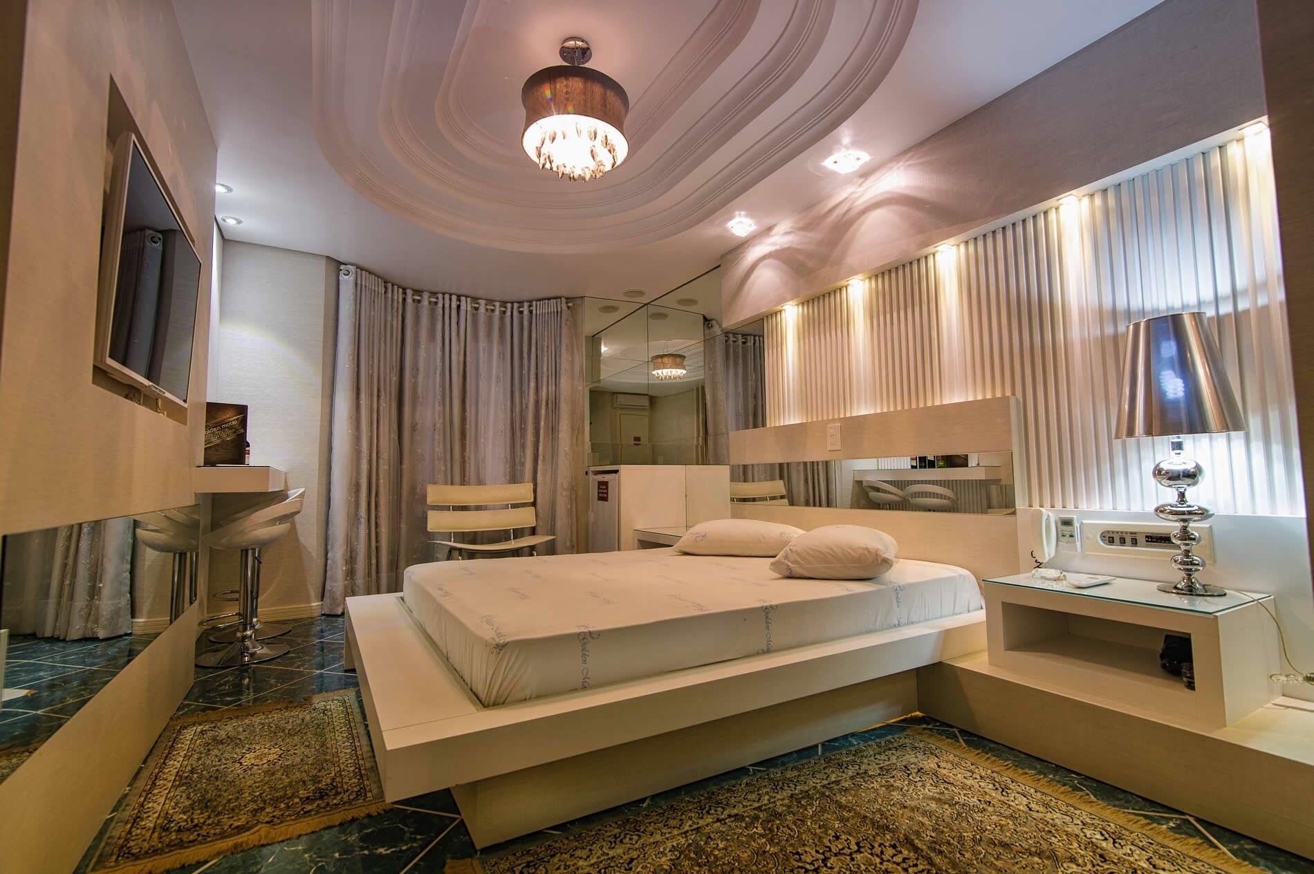 Una habitación de hotel moderna con una cama grande, un tocador, un escritorio y una araña.