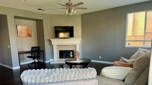 Una sala de estar con chimenea, televisor y ventilador de techo.