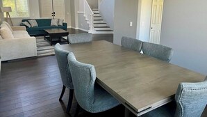 Amplia sala de estar con comedor, una escalera y una puerta que da a otra habitación.