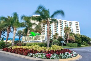 Schild des The Palms of Destin Resort & Conference Center mit angelegtem Garten und Palmen.