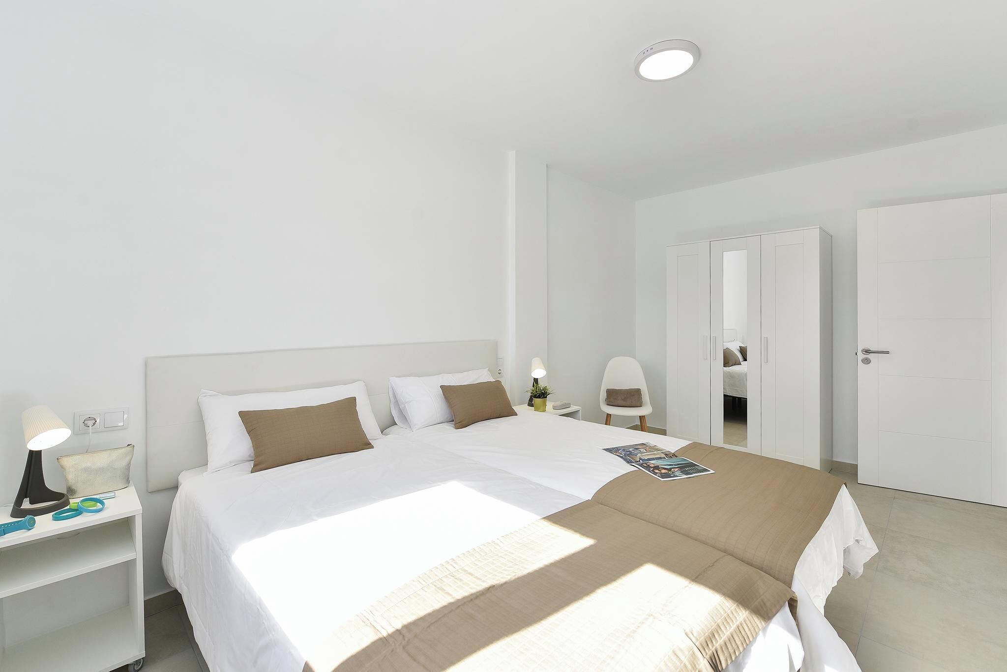 Habitación de hotel con una cama grande, mesitas de noche, una lámpara y una puerta.