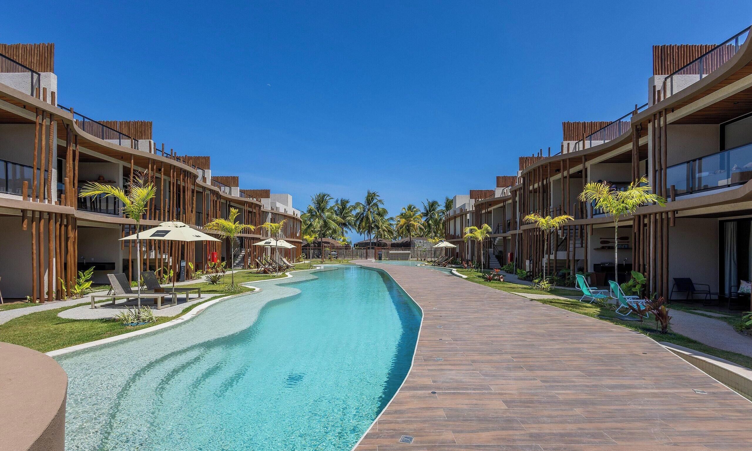 A resort with a swimming pool, wooden deck, and multiple-story buildings with balconies.