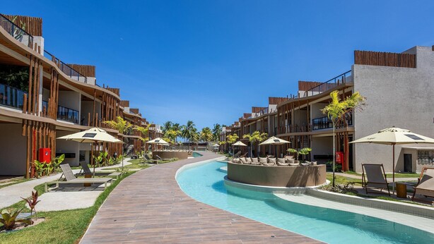 A resort with a swimming pool, lounge chairs, and palm trees. - Apartments in Condo With Pool in Front of the Beach - NVB (Porto de Pedras)