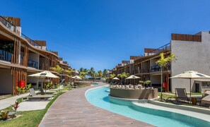 A resort with a swimming pool, lounge chairs, and palm trees. - Apartments in Condo With Pool in Front of the Beach - NVB (Porto de Pedras)