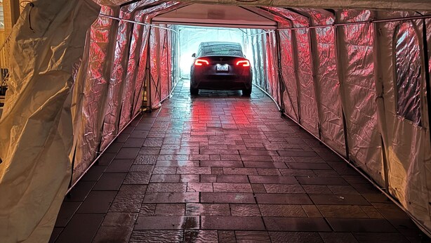 Un automóvil circulando por un túnel techado con el suelo mojado.
