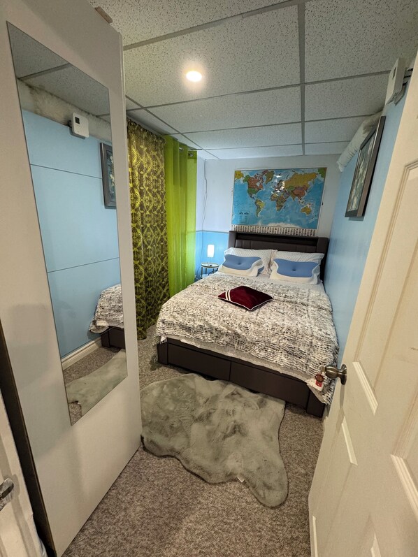 Un dormitorio con una cama, un mapa en la pared, un espejo y una cortina verde.