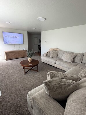 A living room with a sofa, a coffee table, a TV displaying 'WELCOME,' and a decorative plant.