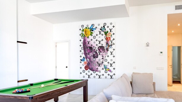 Ein modernes Wohnzimmer mit Billardtisch, einer Couch und einer Wand mit einem dekorativen Gemälde.