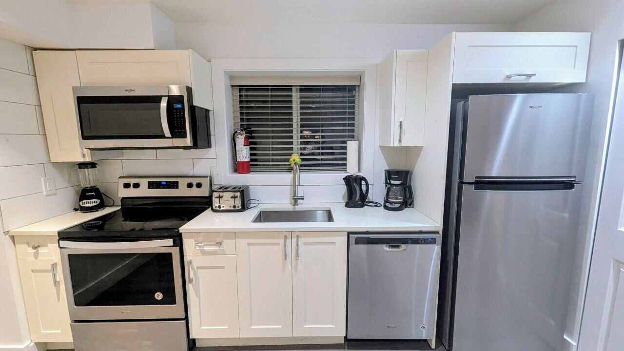 Una cocina compacta equipada con microondas, estufa, horno, lavaplatos y refrigerador.