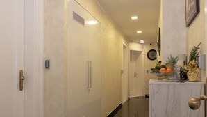 A hallway with a white door, a white cabinet with a fruit bowl, and a clock on the wall. - Queen Teuta Luxury Rooms Split (Split)