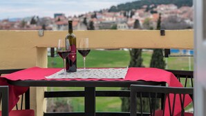 A table with a red tablecloth and two wine glasses, a bottle of wine, and a placemat. - Queen Teuta Luxury Rooms Split (Split)