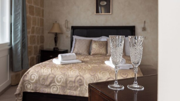 A hotel room with a bed, two bedside tables, a lamp, and two crystal glasses on a table. - Queen Teuta Luxury Rooms Split (Split)