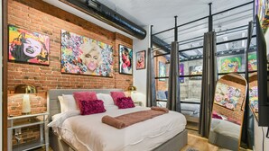 Een moderne slaapkamer met een bakstenen muur, een groot bed en kunstwerken.