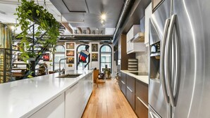 Een moderne keuken met een roestvrijstalen koelkast, houten vloeren en een groot kookeiland.