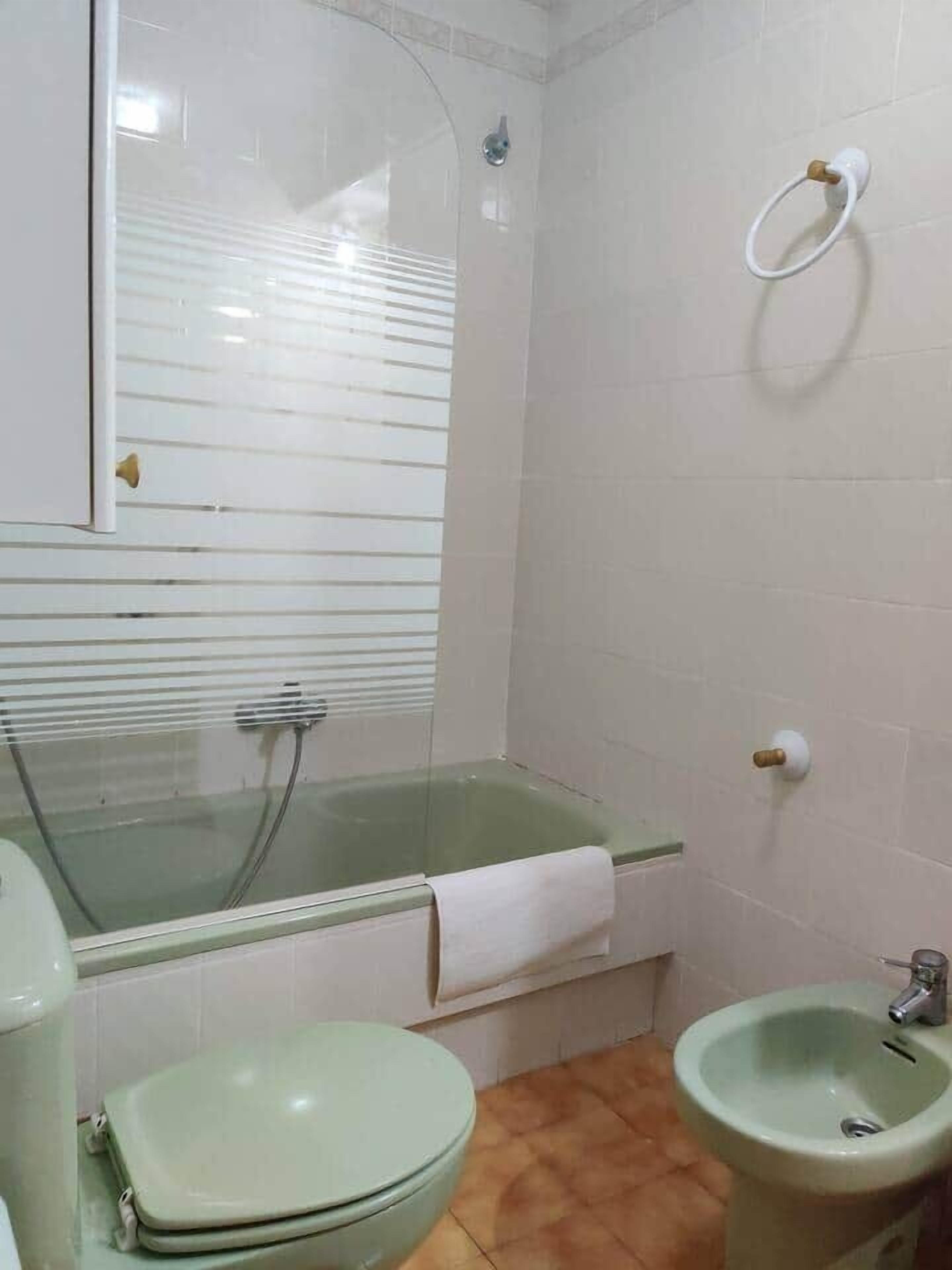 Un baño con ducha de vidrio, inodoro y lavabo.