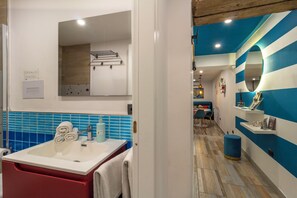 A bathroom with a sink, mirror, towel rack, and blue-tiled wall. - Mooniq Toledo Apartment   (Napoli)