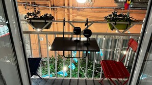 En balkong med ett bord, stolar, krukväxter och en hängande lampa.