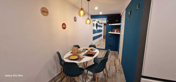 A modern dining area with a round table, dark chairs, and hanging pendant lights. - Mooniq Toledo Apartment   (Napoli)