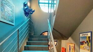 A staircase with blue-tinted steps, a handrail, and artwork on the walls. - DOMUS HOTEL (Luxembourg City)