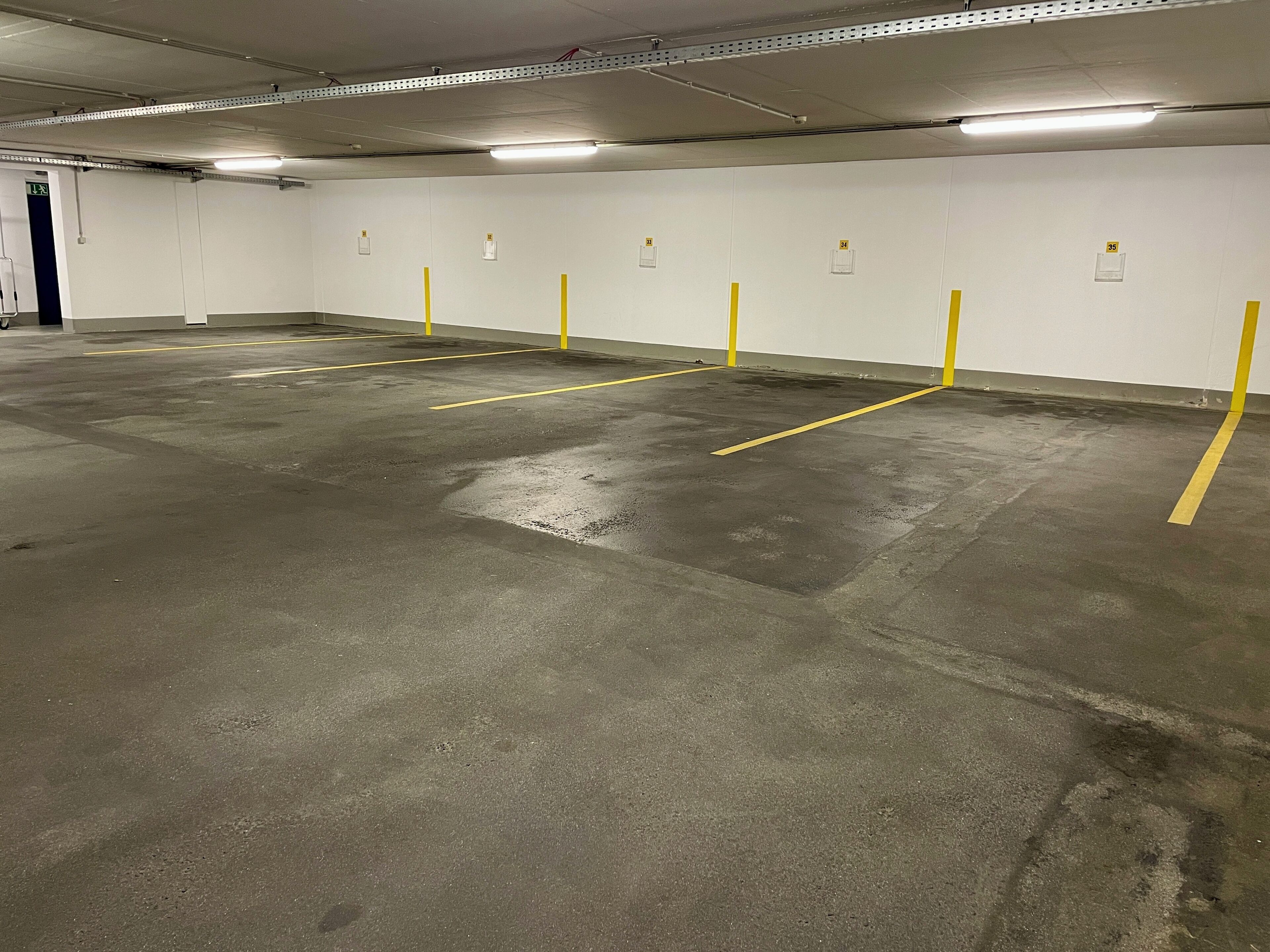 Un garaje con espacios de estacionamiento delimitados y una puerta que da a una salida.