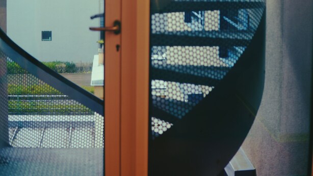 A spiral staircase with a glass railing, leading to an upper floor. - DOMUS HOTEL (Luxembourg City)