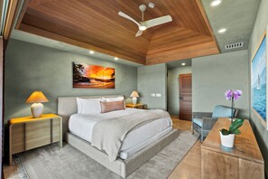 A bedroom with a bed, nightstands, a desk, a chair, a ceiling fan, and a painting on the wall.