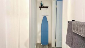 Un couloir avec une porte bleue, un mur blanc et un plancher en bois.