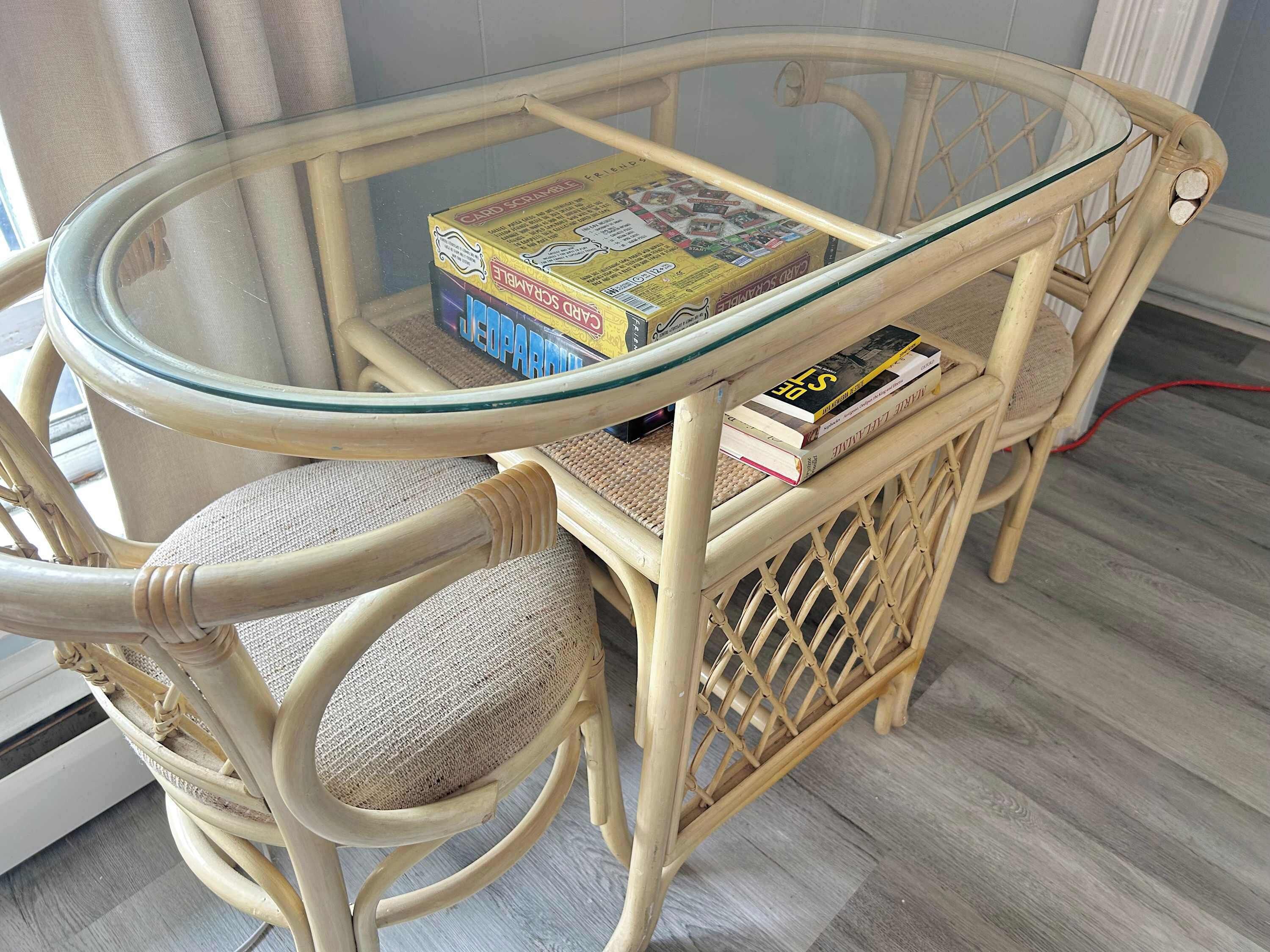 A wicker chair with a glass-top table, a box of cards, and a book.