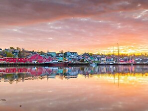 A waterfront town with colorful buildings reflected in calm water during sunset.