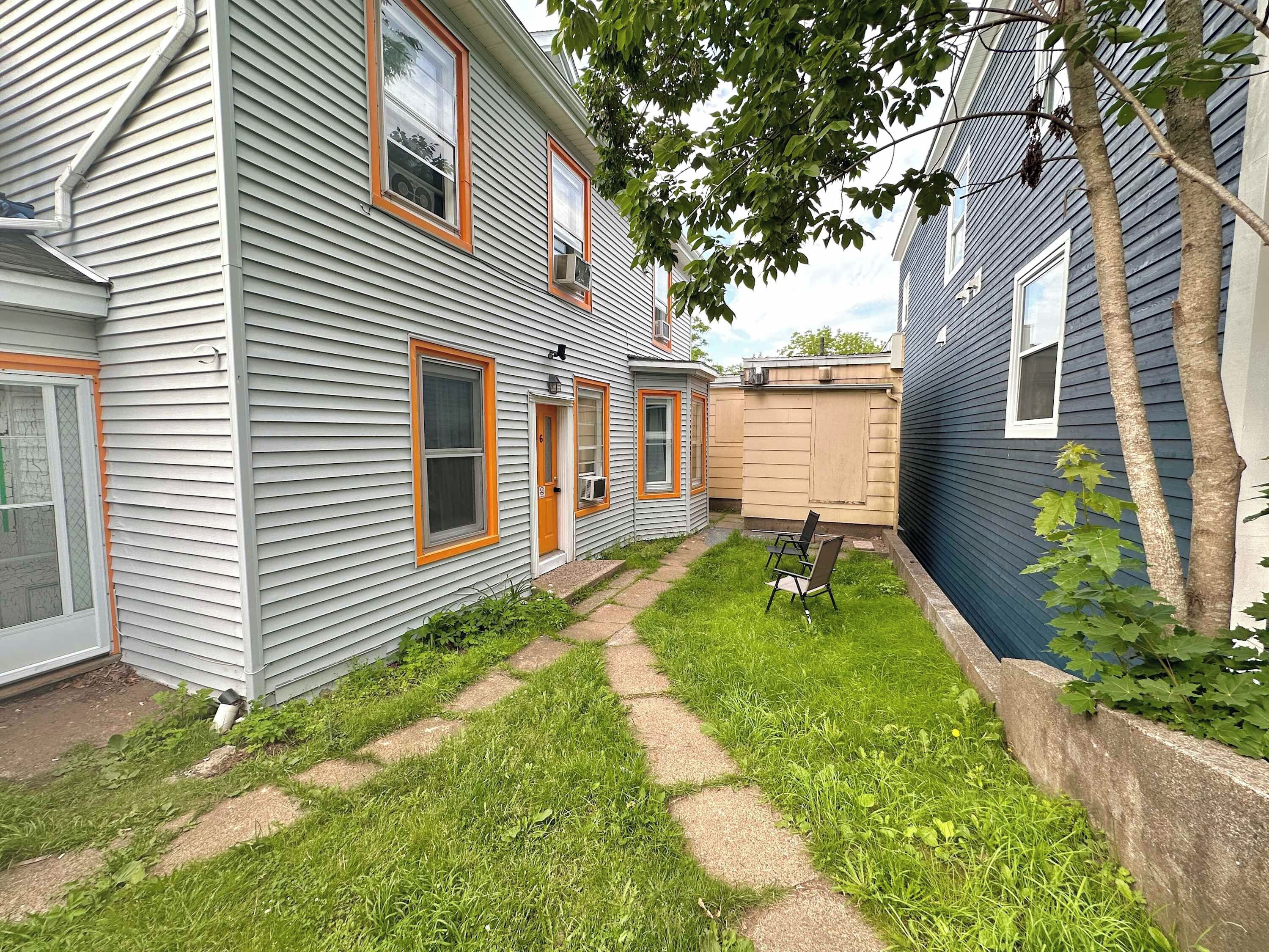 A residential property with a paved pathway, a small lawn, and a wooden fence.
