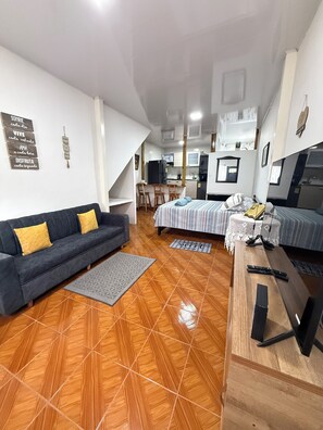 Ein kompakter Wohnbereich mit Sofa, Bett, einer kleinen Küche und einem Esstisch.