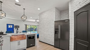 Una cocina moderna con armarios blancos, un lavamanos de cobre integrado y un refrigerador de acero inoxidable.