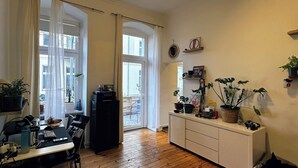A spacious living area with wooden flooring, a dining table, and a kitchen area with cabinets and a countertop. - Quiet Altbau 2-Room Apartment with Terrace | Central Berlin near Parks & S-Bahn (Berlin)