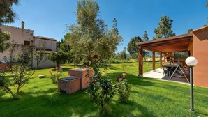 A well-maintained garden with a pergola, outdoor seating, and a clear view of the surrounding landscape. - Villa Giulietta - Castiadas (Castiadas)