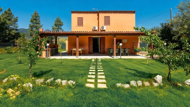 A two-story house with a covered patio, a stone pathway leading to the entrance, and a well-maintained lawn. - Villa Giulietta - Castiadas (Castiadas)