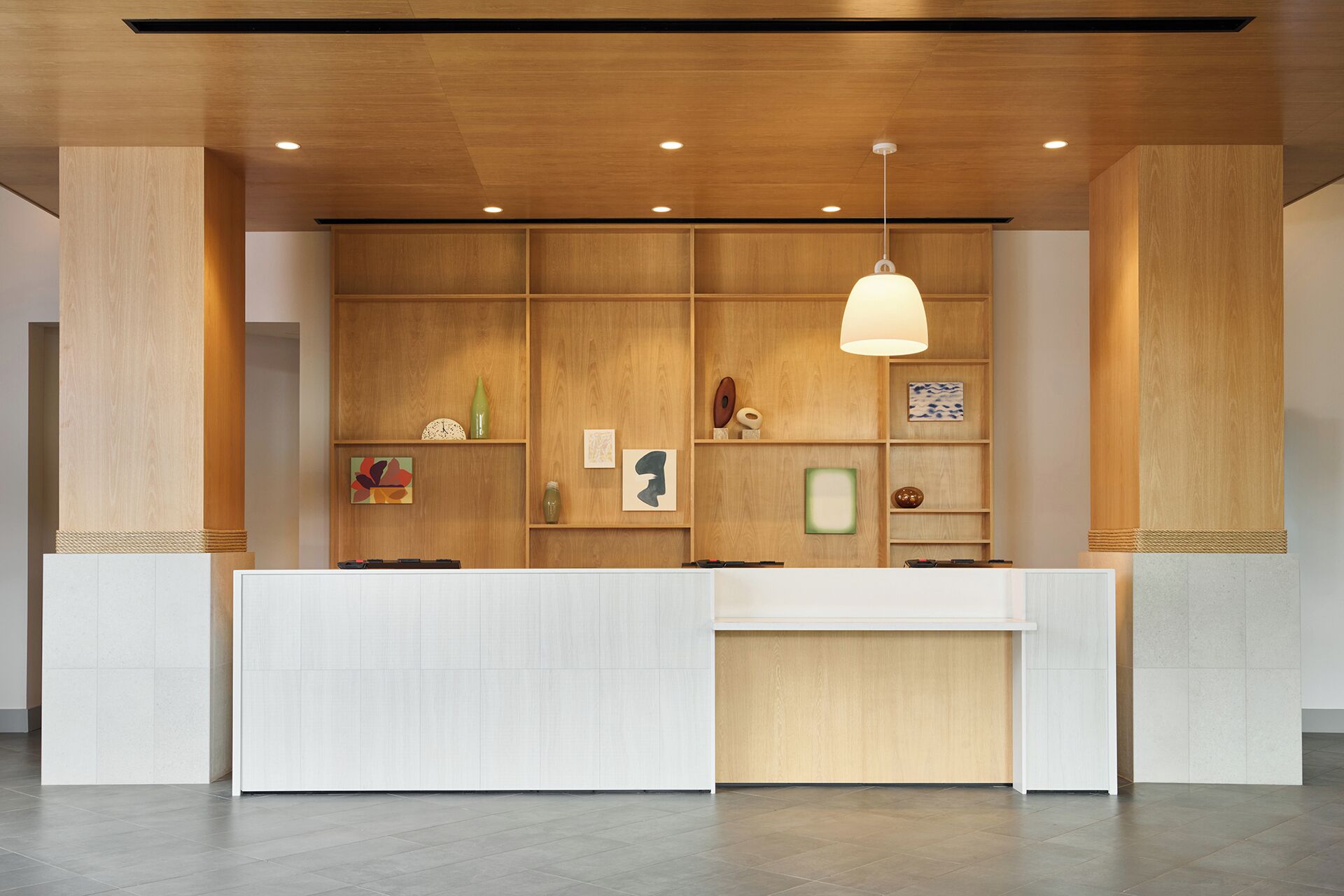 A reception desk with a wooden panel wall, a hanging pendant light, and a tiled floor.