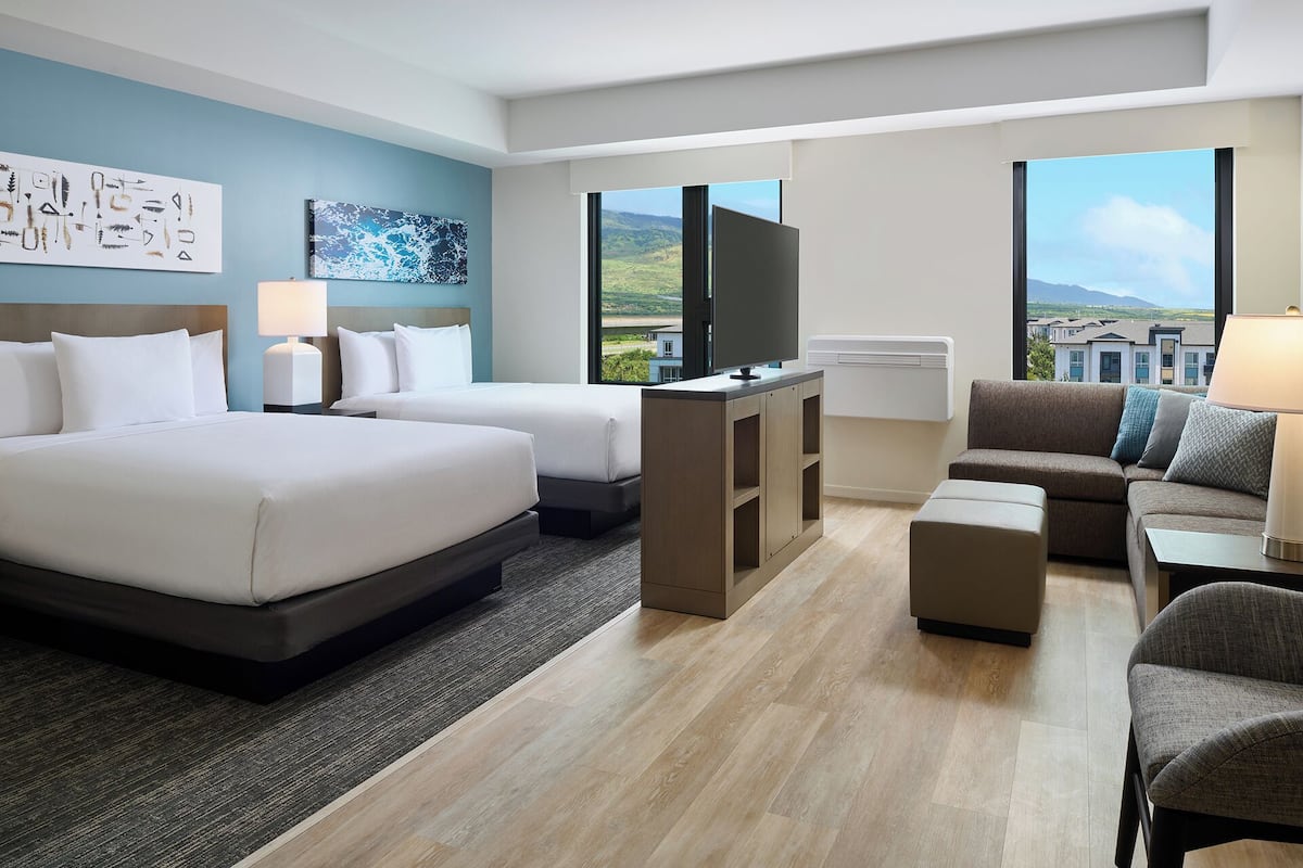 Une chambre d’hôtel avec deux lits, une télévision, un canapé et une vue sur la campagne.