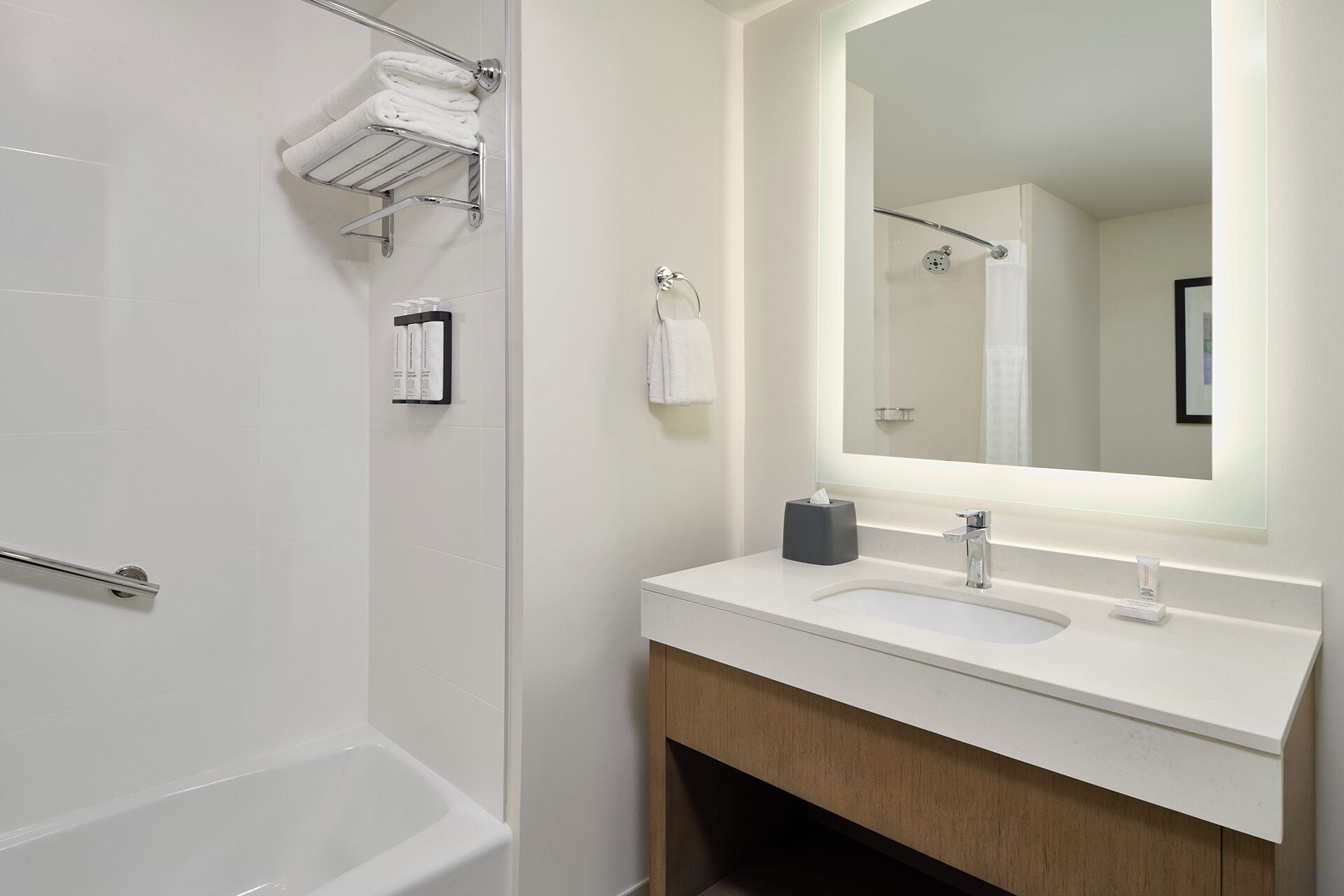 A modern bathroom with a bathtub, a sink with a mirror, and a towel rack.