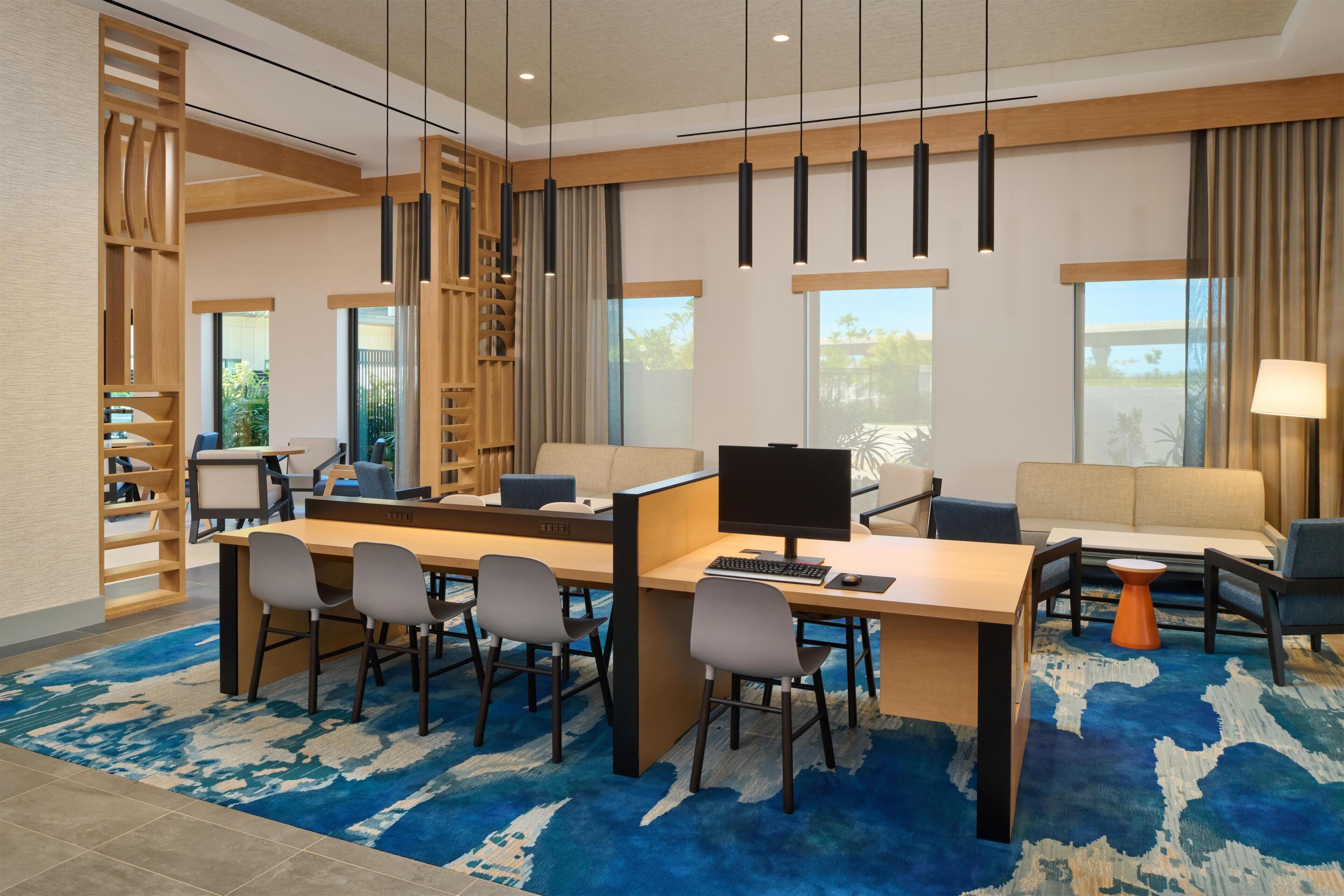Una habitación de hotel moderna con un escritorio grande, computadora y zona de estar.