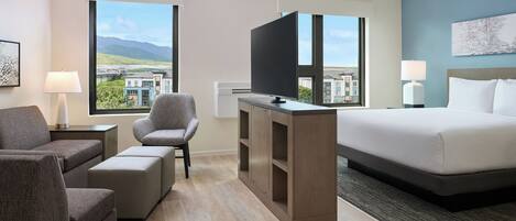 Une chambre d’hôtel avec un lit, un téléviseur posé sur un meuble, une chaise, un canapé et un bureau.
